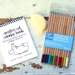 "Creative Cat Coloring Book" with watercolor pencils and art sponge.